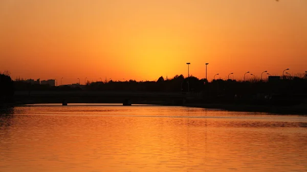 街の川の近くに水の反射と美しい夕日の景色 — ストック写真