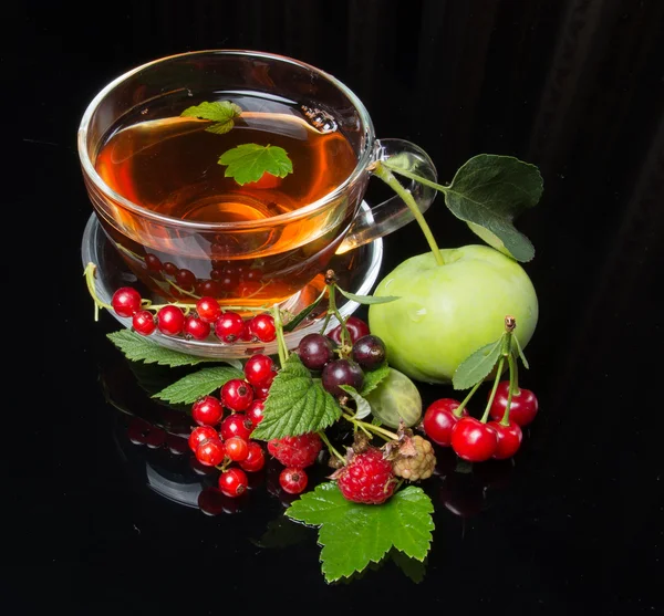 Tea with berry cuts on black background — Stock Photo, Image