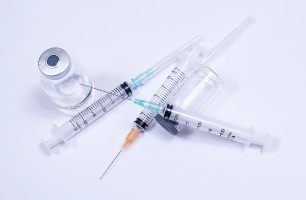 Injekční stříkačka s kapičky a lékařské na bílém pozadí. — Stock fotografie