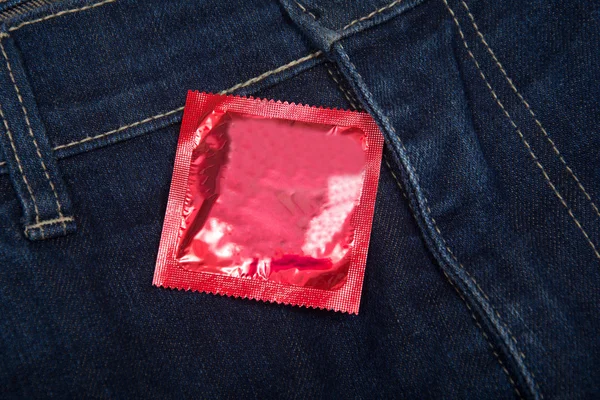 Preservativo no bolso das calças de ganga. Textura, fundo . — Fotografia de Stock
