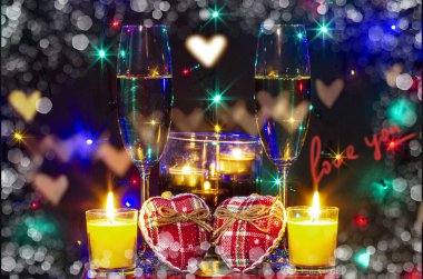 İki kalp, iki kadeh şarap, arka planda mumlar olan üç şamdan ve siyah arkaplanda 