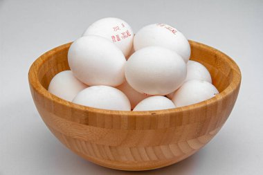 Birçok yumurta, bir ışık masasındaki ahşap bir kasede yatar. Yan görünüm.
