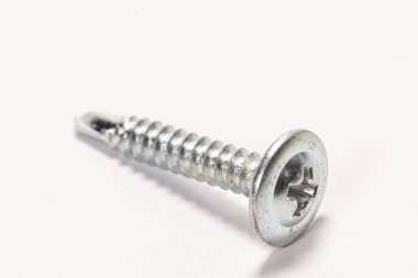 Metal için bir inşaat vidası hafif arkaplanda yatıyor.