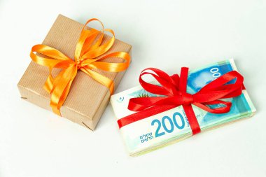 Bir hediye ve 200 yeni İsrail şekeri. Kırmızı kurdeleyle bağlanmış banknotlar açık arkaplanda..