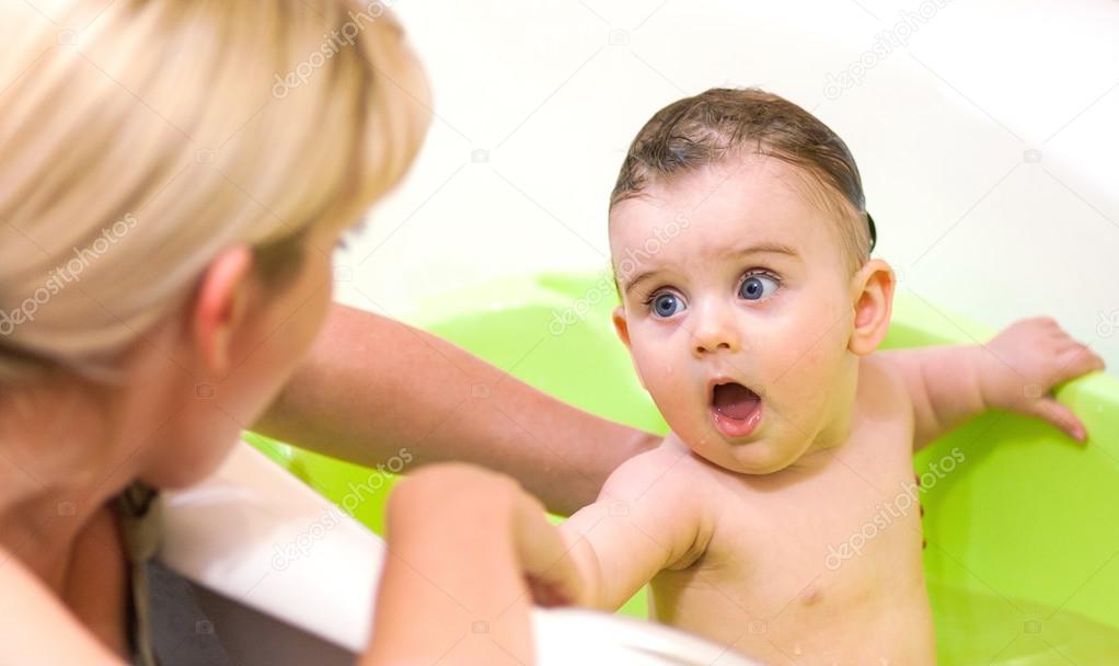 small child bathes in a bath with his mother.