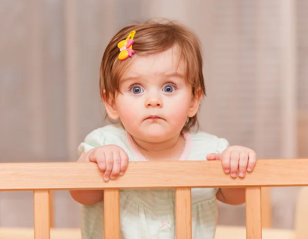 Klein kind met een haarspeld staande in wieg. — Stockfoto