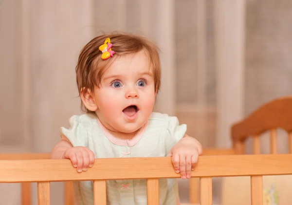 Small child with a hairpin standing in crib. — Stock Photo, Image