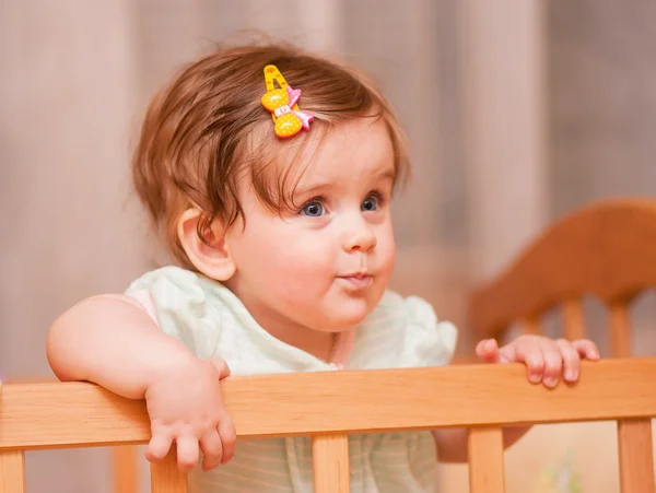 Small child with a hairpin standing in crib. — Stock Photo, Image