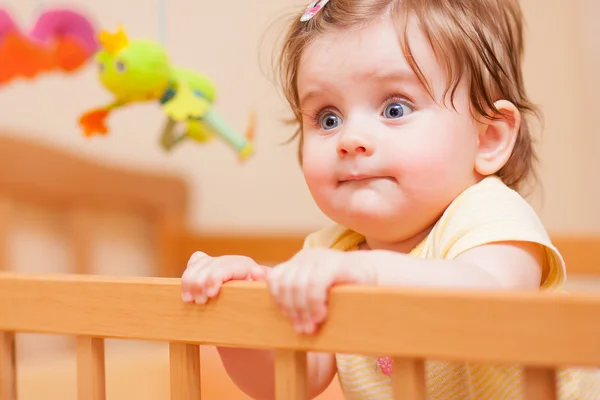 Small child with a hairpin standing in crib — Stock Photo, Image