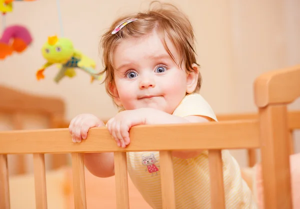 Criança pequena com um grampo de cabelo em pé no berço . — Fotografia de Stock
