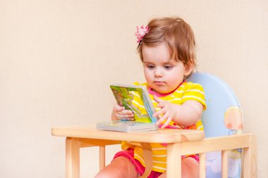 kitap önünde bir masada oturan küçük kız.