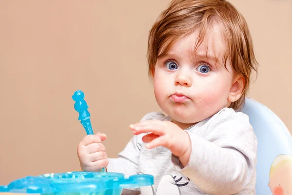 A criança pequena senta-se a uma mesa e come . — Fotografia de Stock