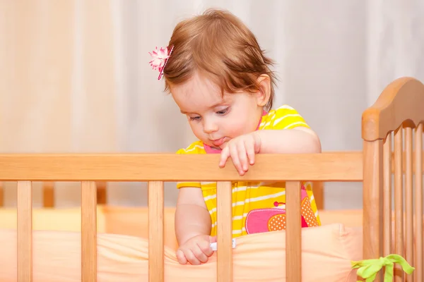 Small child with a hairpin standing in crib. — Stock Photo, Image