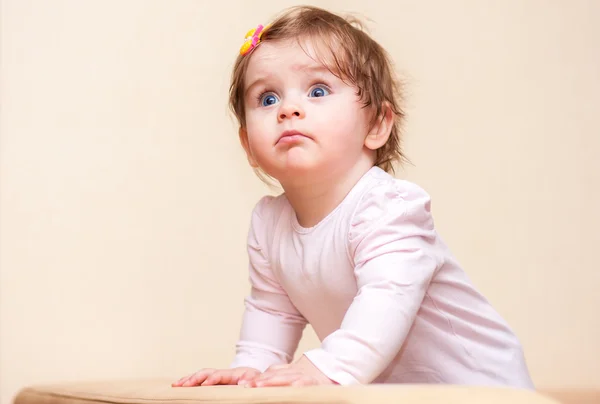 Little girl stands near the sofa at home. — Stock Photo, Image