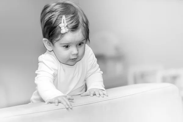 Little girl stands near the sofa at home. — Stock Photo, Image