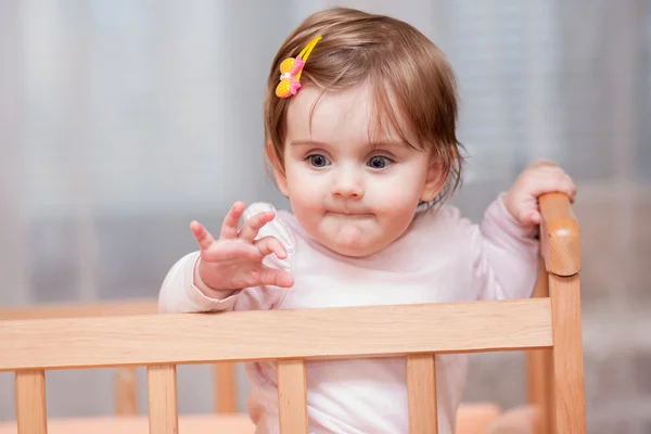 Small child with a hairpin standing in crib. — Stock Photo, Image