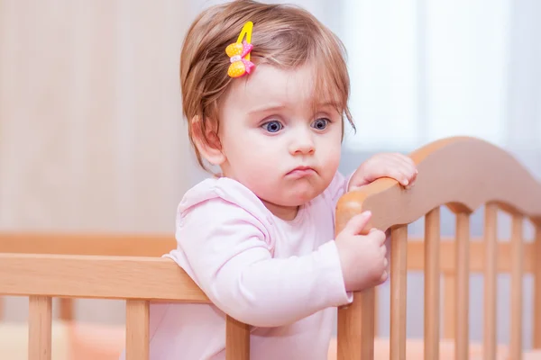 Small child with a hairpin standing in crib. — Stock Photo, Image