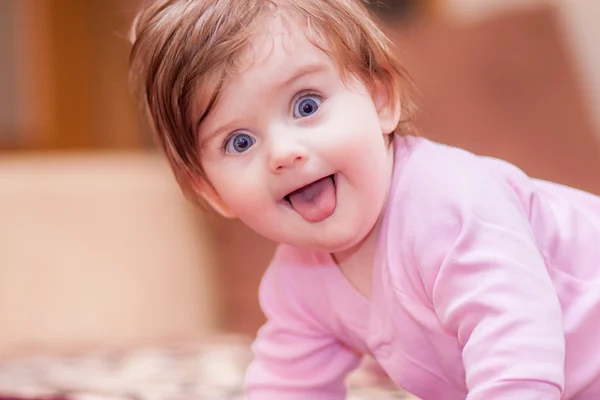 Baby liegt auf der Decke und zeigt Zunge. — Stockfoto