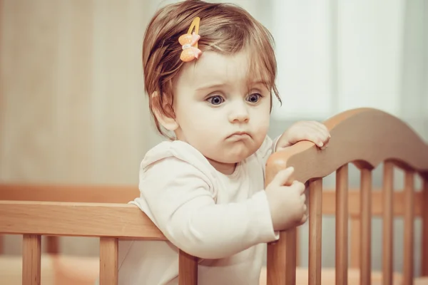 Small child with a hairpin standing in crib. — Stock Photo, Image