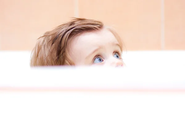 Malé roztomilé dítě koukat z vany. — Stock fotografie