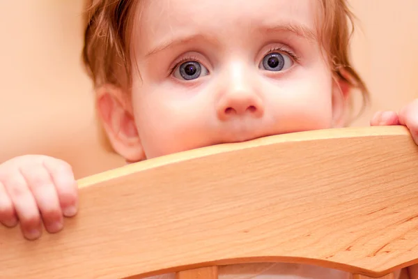 Small child standing peeps out cot — Stock Photo, Image