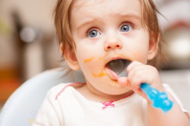 küçük kız mavi sandalye üzerinde bir kaşık besleme.