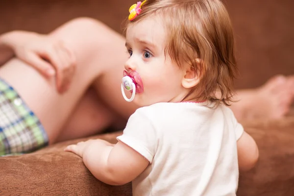 Little girl stands near the sofa — Stock Photo, Image