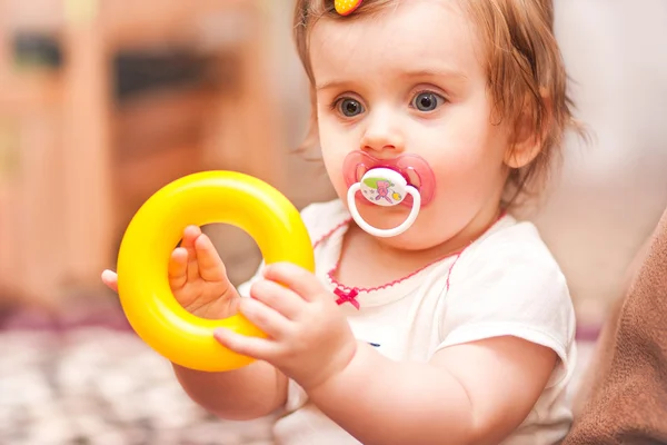 Little girl sitting playing with a toy ring. — Stock Photo, Image