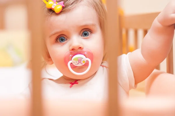 Little girl sitting in a crib with — Stock Photo, Image