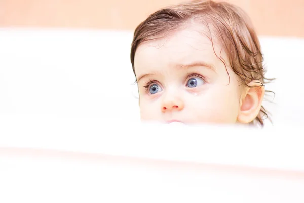 Criança pequena senta-se em um banho branco — Fotografia de Stock