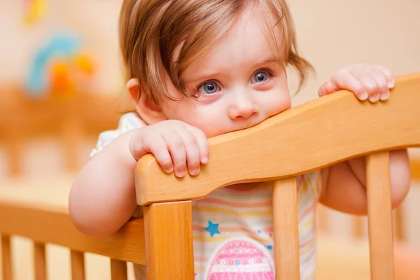 Liten flicka stående i spjälsängen — Stockfoto