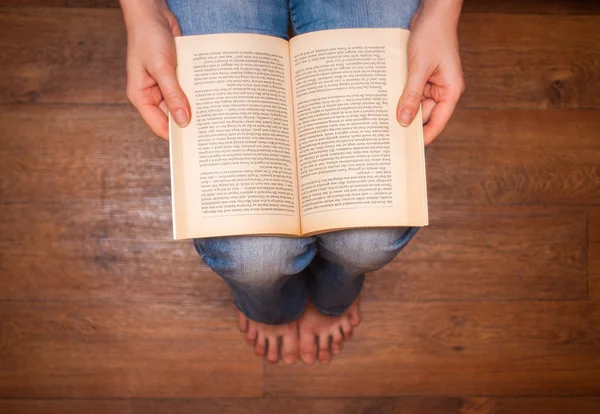 Mädchen in Jeans sitzt und liest ein Buch. — Stockfoto