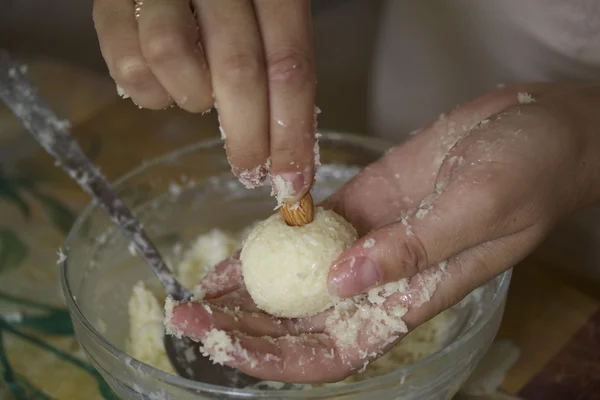Vrouw maken van snoep. Het duwt de amandelen in een bal van kokosnoot. — Stockfoto