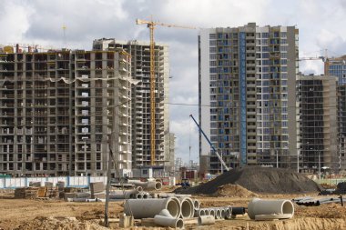 Modern çok katlı binaların yapımı. Yerleşim alanının yeni gelişimi. İnşaat alanında ev iskeletleri, inşaat vinçleri ve inşaat malzemeleri.