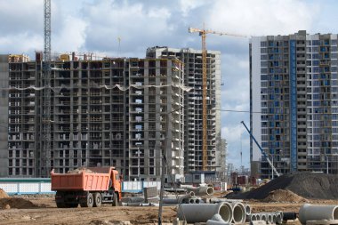 Modern çok katlı binaların yapımı. Yerleşim alanının yeni gelişimi. İnşaat alanında ev iskeletleri, inşaat vinçleri ve inşaat malzemeleri.