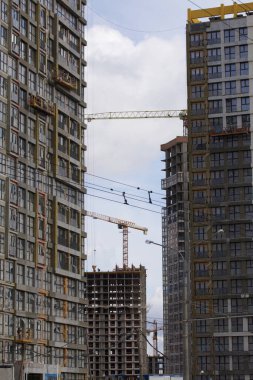 Modern çok katlı binaların yapımı. Yerleşim alanının yeni gelişimi. İnşaat alanında ev iskeletleri ve inşaat vinçleri.