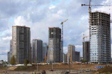 Modern çok katlı binaların yapımı. Yerleşim alanının yeni gelişimi. İnşaat alanında ev iskeletleri, inşaat vinçleri ve inşaat malzemeleri.