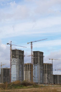 Modern çok katlı binaların yapımı. Yerleşim alanının yeni gelişimi. İnşaat alanında ev iskeletleri, inşaat vinçleri ve inşaat malzemeleri.