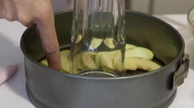 Bir kadın Charlotte 'un pişirme kabına elma dilimleri koyar. Yakın plan.