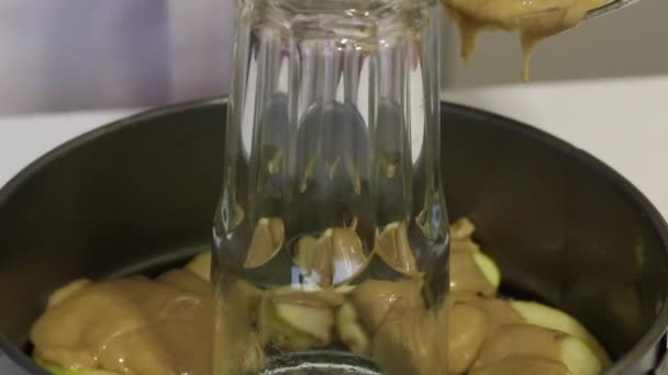 A woman pours the dough into a charlotte baking dish. On top of the apple slices. Close-up — Stock Video