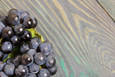 Koyu mavi üzümler. Siyah yeşil çam tahtalarında yatıyor.