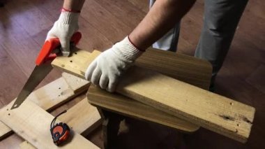 Bir adam demir testeresiyle tahta testeresi kesiyor. Sebze toplamak için bir depolama kutusu yapıyor. Bir apartman dairesinde salgın sırasında sebze toplamak..