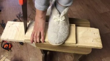 Bir kadın demir testeresiyle tahtayı kesiyor. Sebze depolamak için bir kutu yaptığım için. Bir apartman dairesinde salgın sırasında sebze toplamak. Yan taraftan yakın çekim..