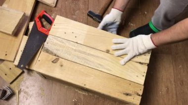 Adam devrilmiş tahtaları çekiçle düzeltiyor. Sebze toplamak için bir depolama kutusu yapıyor. Bir apartman dairesinde salgın sırasında sebze toplamak..