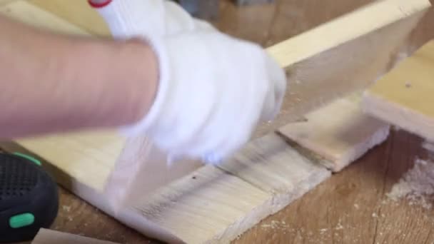 De man vouwt de planken. Maakt een opbergdoos voor het oogsten van groenten. Groenten oogsten tijdens de epidemie in een stadsappartement. — Stockvideo