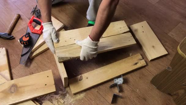 L'uomo abbatte le tavole con i chiodi. Crea una scatola di immagazzinaggio per la raccolta di verdure. Raccolta di verdure durante l'epidemia in un appartamento in città. Primo piano. — Video Stock