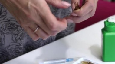 Kadın ampulü açar ve enjeksiyondan önce şırıngayı alır. Yakın çekim..