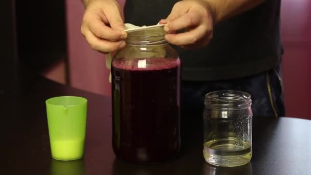 Muž dá gumovou rukavici na sklenici hroznového džusu. Výroba domácího vína během epidemie. — Stock video