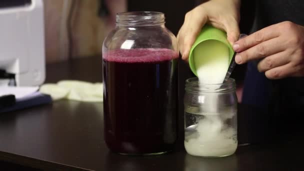 Mannen tillsätter socker i vattnet och blandar. För blandning med druvsaft. Göra hemlagat vin under en epidemi. Närbild. — Stockvideo