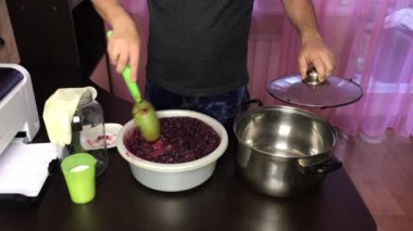 Adam mayalanan üzüm hamurunu karıştırıyor. Salgın sırasında ev yapımı şarap yapmak..